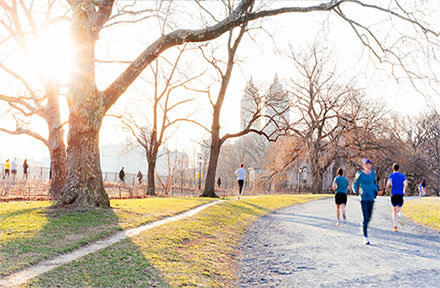 People are running and walking in a large park during the day