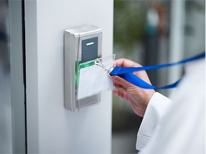 A staff member is unlocking the door by holding a card against access control
